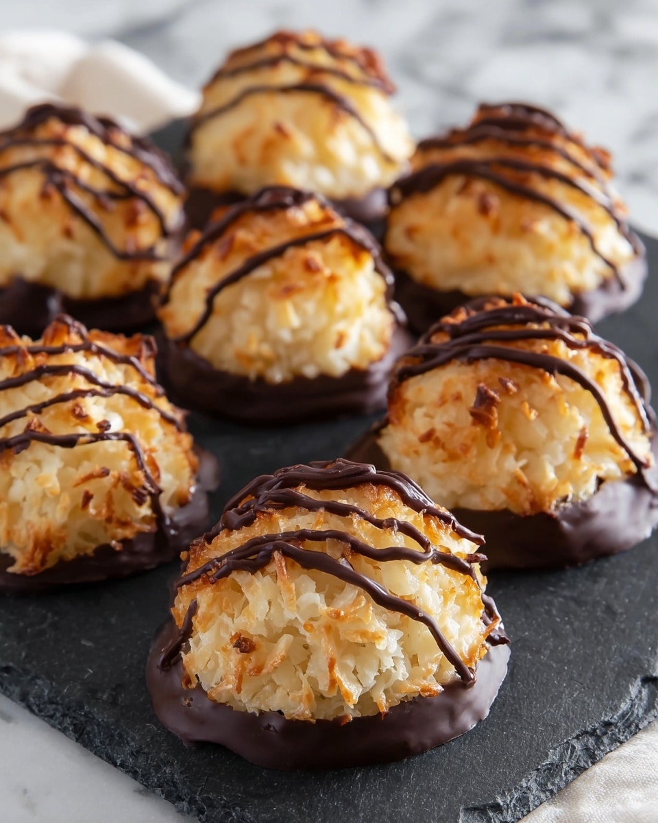 The image shows several dome-shaped coconut macaroons arranged on a black slate serving board placed over a white marbled surface. Each macaroon has three layers: the bottom layer is a thick, dark brown chocolate coating forming a solid base; the middle layer is a golden-brown, crispy coconut exterior with visible shredded coconut texture; the top layer has thin, dark chocolate drizzles artistically spread in wavy lines over the golden coconut peaks. The macaroons are close together, showing their rough, slightly crunchy texture contrasted with the smooth chocolate drizzle. photo taken with an iphone --ar 4:5 --v 7